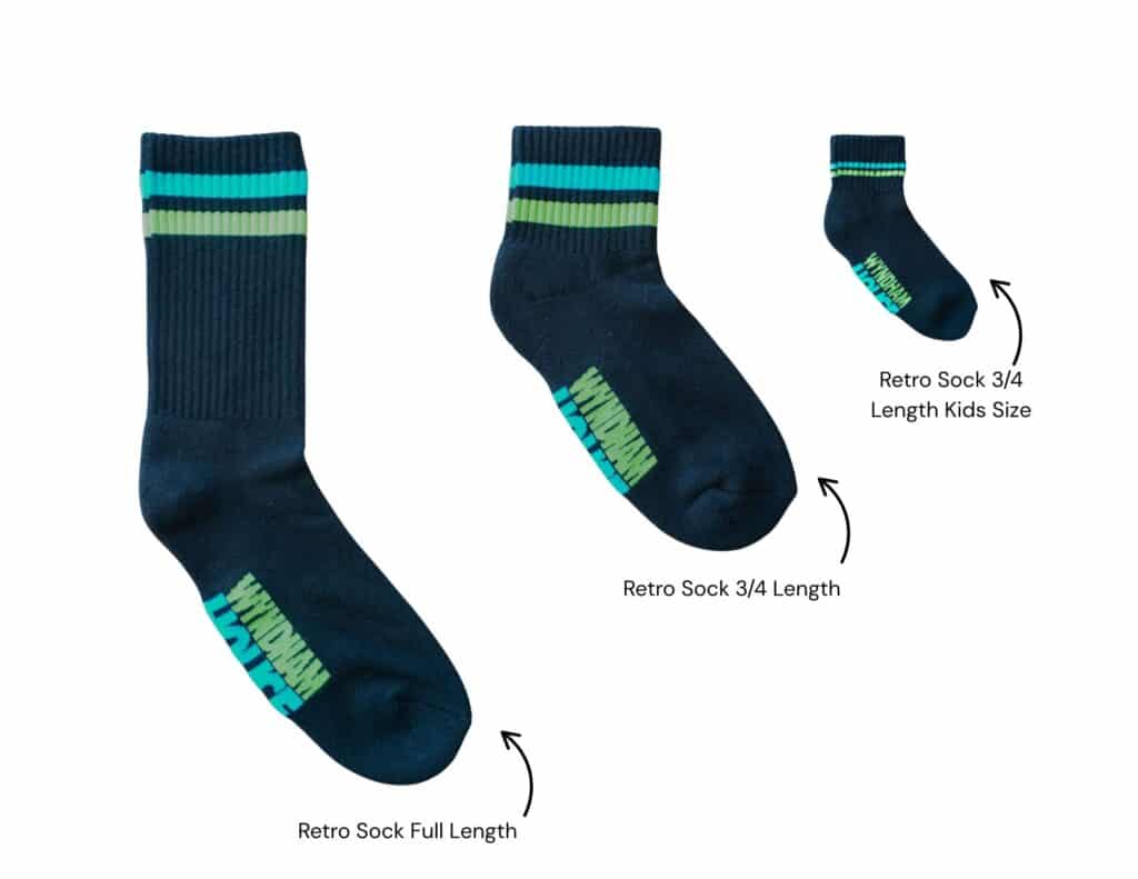 Shows the three sizes and design of the black crew sock for the Wyndham House socks for shelter campaign. The sock design is a black sock with on green stripe and one blue stripe at the top.